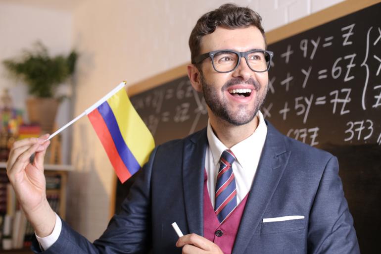 Docente sonriendo con la bandera de Colombia en la mano